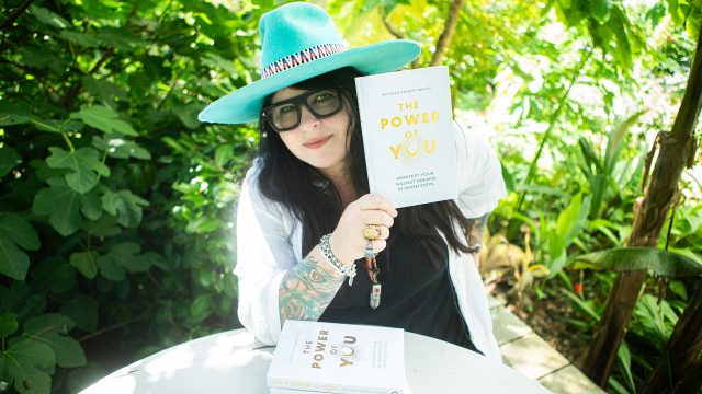Michele Knight-Waite sitting in her garden with her new book: The Power Of You